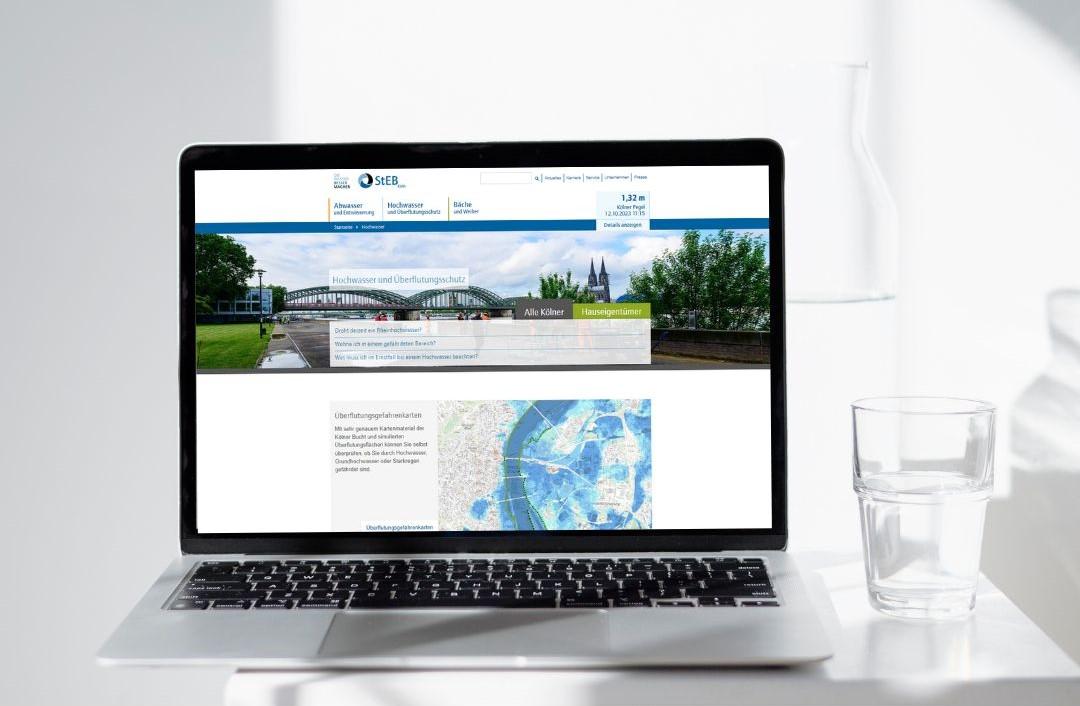 Laptop mit StEB-Webseite mit Wasserglas und Flasche